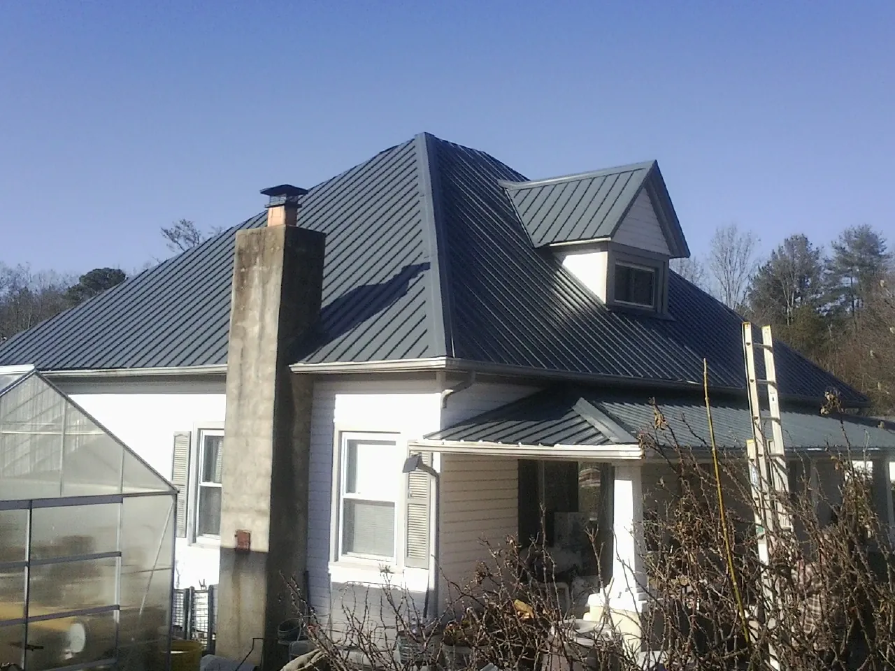 Dark blue standing seam metal roof on a white farmhouse with dormer — Slate & Tile Roof Repair by Roofing Brothers in Cohutta