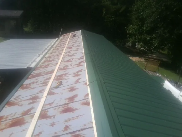 Old rusted panels beside newly installed green metal roofing — Wind Damage Roof Repair by Roofing Brothers in Cohutta