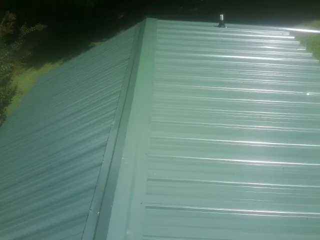 New green metal panels meeting at the ridge of a roof — Flat Roof Repair work by our crew in Cohutta