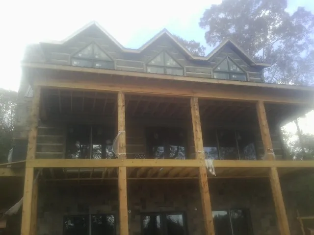 Dormers and porch framing on a large log home under construction — Roof Coating work by our crew in Cohutta