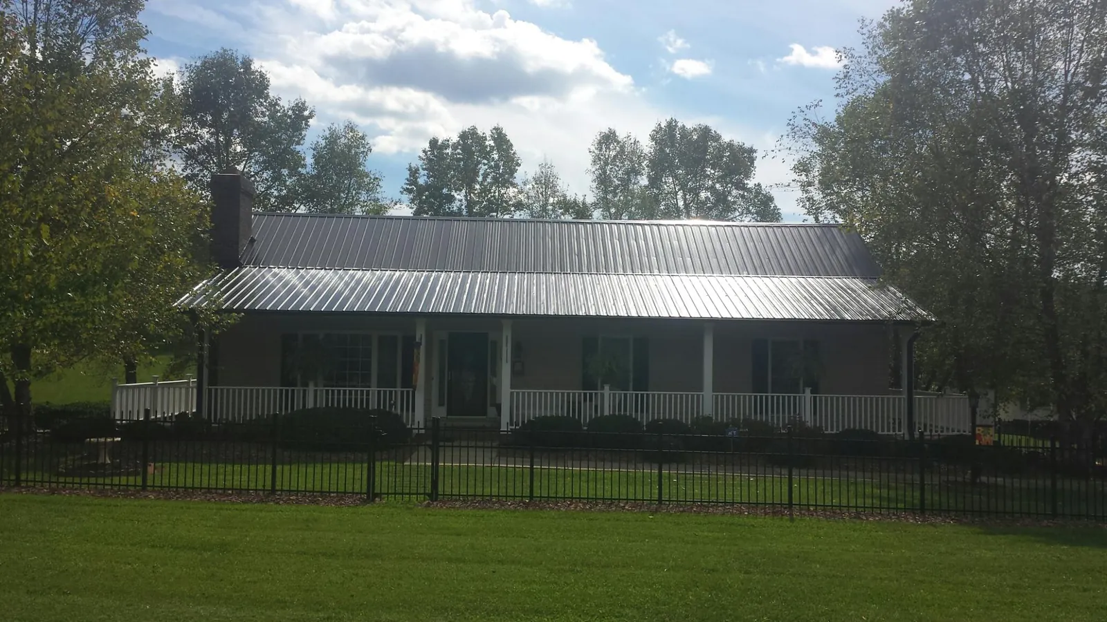 Gray metal roof on a brick ranch with a full width front porch — Gutter Guard Installation work by our crew in Cohutta