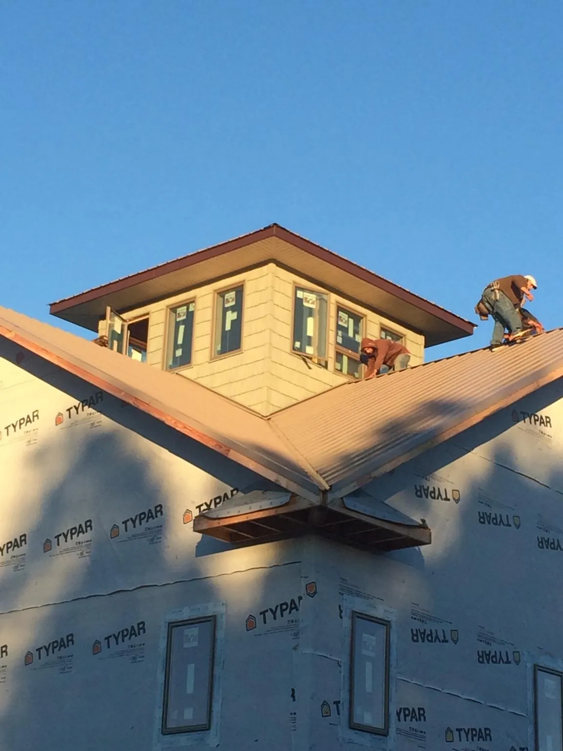 Roofers working around a rooftop cupola on a new metal roof at sunset — Roof Waterproofing in Cohutta by Roofing Brothers